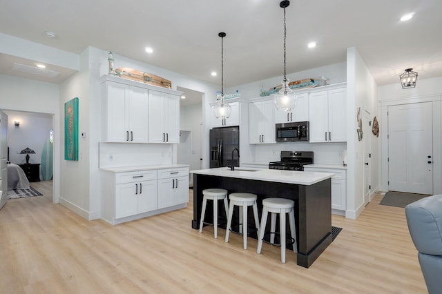 653 W Arbor Glenn Dr, Nixa, MO 65714 - kitchen with range with gas cooktop, stainless steel microwave, black refrigerator with ice dispenser, a breakfast bar area, and light wood finished floors