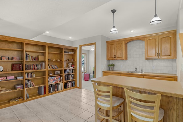 1190 E Headley St, Springfield, MO 65803 - kitchen with light countertops, a kitchen bar, light tile patterned flooring, decorative light fixtures, and decorative backsplash