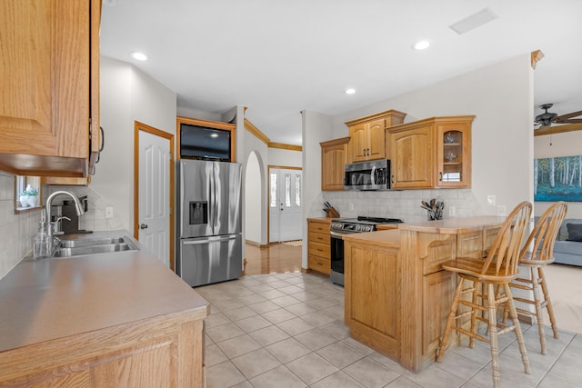 1190 E Headley St, Springfield, MO 65803 - kitchen with stainless steel appliances, a peninsula, a breakfast bar, glass insert cabinets, and decorative backsplash