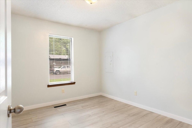 1219 N Clifton Ave, Springfield, MO 65802 - empty room featuring light wood-style flooring, electric panel, and a textured ceiling