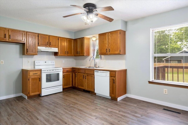 1219 N Clifton Ave, Springfield, MO 65802 - kitchen with white appliances, under cabinet range hood, tasteful backsplash, light countertops, and a textured ceiling