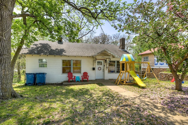 207 W Grand, Neosho, MO 64850 - view of front of house with a chimney, a playground, a front yard, and roof with shingles