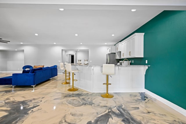 13030 County Lane 228, Oronogo, MO 64855 - kitchen featuring white cabinetry, open floor plan, light stone counters, a kitchen breakfast bar, and freestanding refrigerator