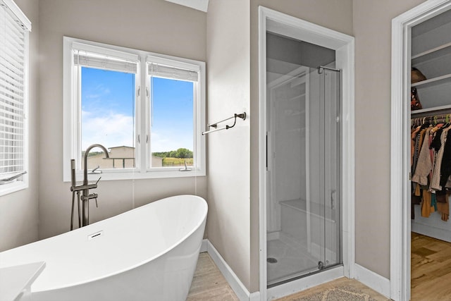4201 N Farm Rd Unit 205, Strafford, MO 65757 - bathroom featuring a spacious closet, a stall shower, a freestanding tub, and wood finished floors
