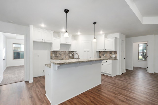 2000 E Greenwich Dr, Ozark, MO 65721 - kitchen with dark wood finished floors, white cabinetry, decorative backsplash, a kitchen island with sink, and light stone countertops