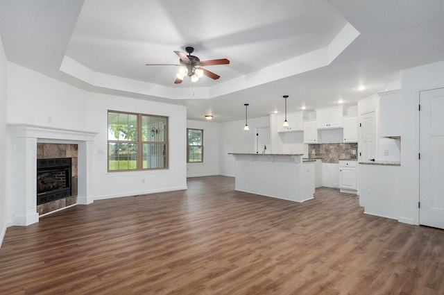 2000 E Greenwich Dr, Ozark, MO 65721 - unfurnished living room featuring a raised ceiling, a ceiling fan, dark wood-style flooring, and a fireplace