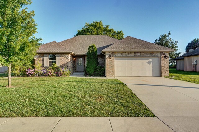2000 E Greenwich Dr, Ozark, MO 65721 - view of front of house with an attached garage, brick siding, and a front lawn
