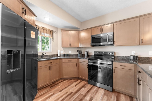 2505 Talking Rocks Rd, Branson West, MO 65737 - kitchen with stainless steel appliances, light wood-style floors, dark stone countertops, and a textured ceiling
