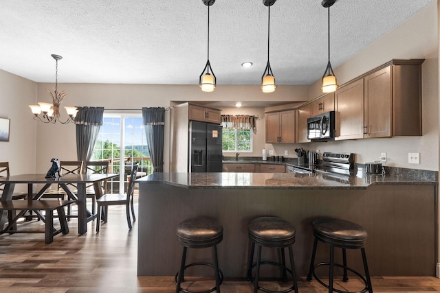 2505 Talking Rocks Rd, Branson West, MO 65737 - kitchen with appliances with stainless steel finishes, healthy amount of natural light, a textured ceiling, dark wood-style floors, and a peninsula