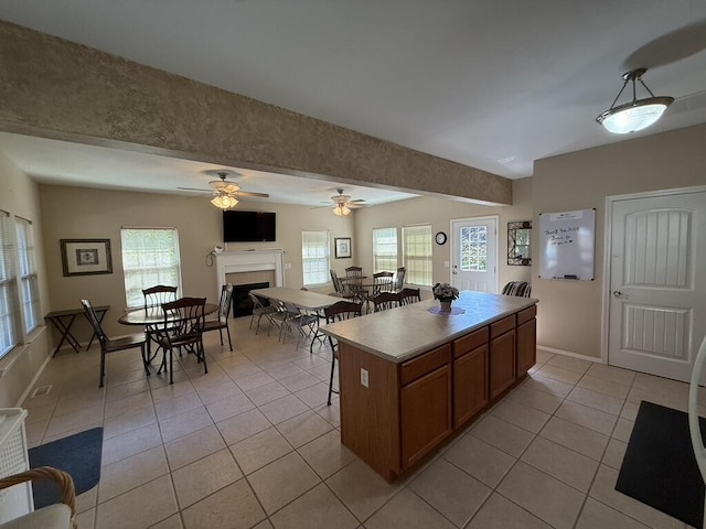 1352 N Sandy Creek Cir Unit 3, Nixa, MO 65714 - kitchen featuring light tile patterned floors, a kitchen island, brown cabinets, a fireplace, and a ceiling fan