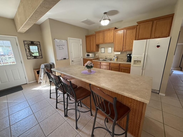 1352 N Sandy Creek Cir Unit 3, Nixa, MO 65714 - kitchen featuring white appliances, light tile patterned floors, light countertops, and a kitchen breakfast bar