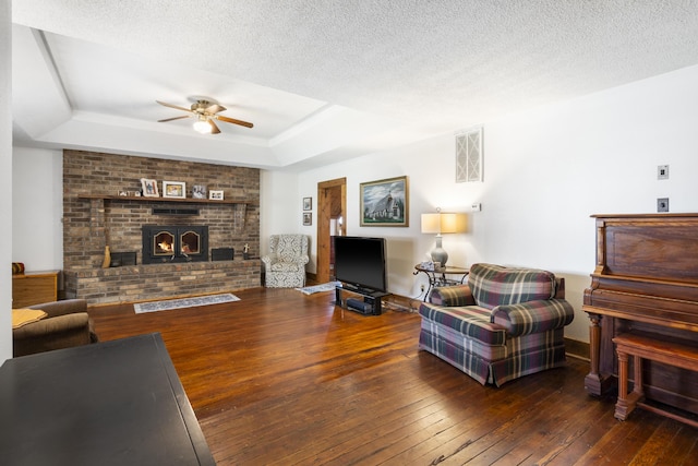 400 E Walker St, Ash Grove, MO 65604 - living area featuring a tray ceiling, a ceiling fan, wood-type flooring, a fireplace, and a textured ceiling