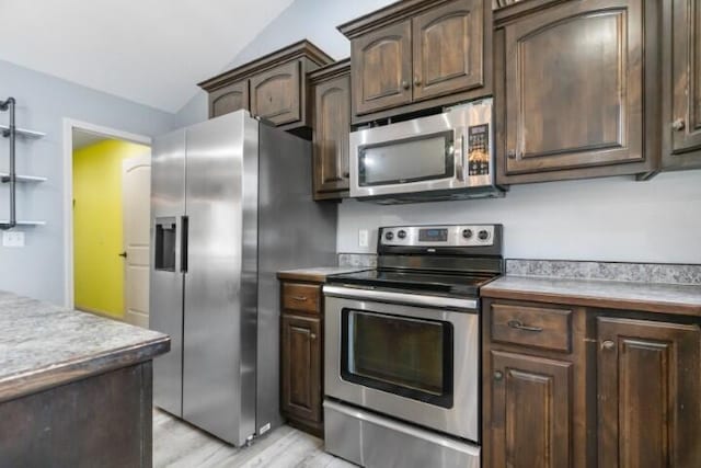 223 Roundhill Rd, Branson, MO 65616 - kitchen featuring appliances with stainless steel finishes, vaulted ceiling, light wood finished floors, dark brown cabinetry, and light countertops