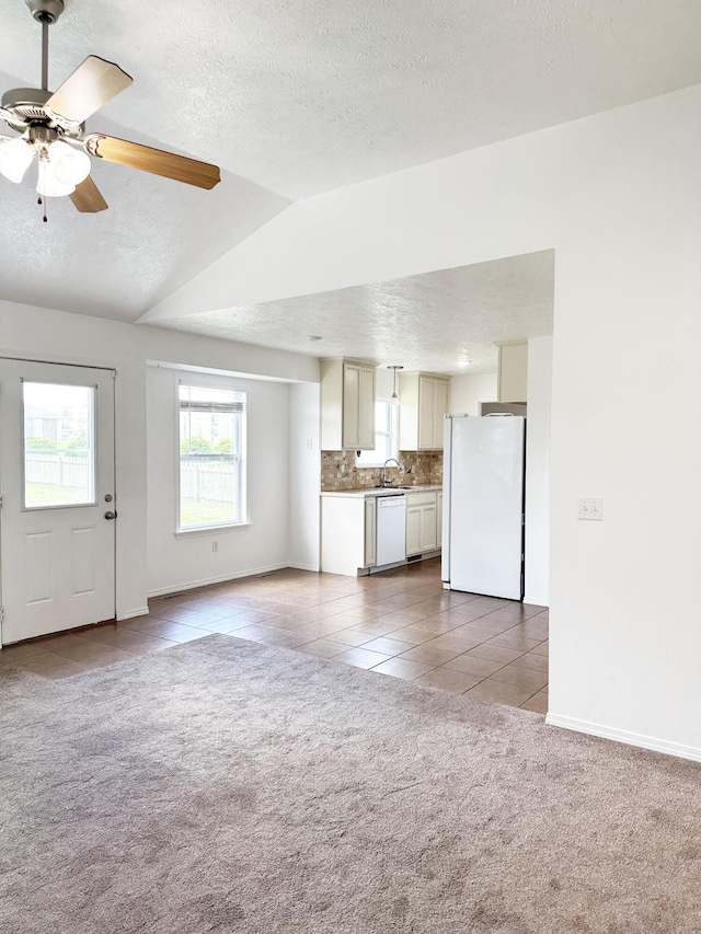 751 Logan St, Rogersville, MO 65742 - unfurnished living room with carpet flooring, a textured ceiling, tile patterned floors, vaulted ceiling, and ceiling fan