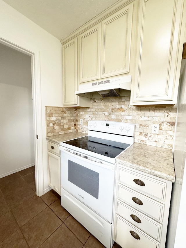 751 Logan St, Rogersville, MO 65742 - kitchen with under cabinet range hood, white electric range oven, backsplash, dark tile patterned flooring, and cream cabinetry