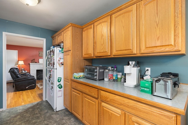 1704 E Latoka St, Springfield, MO 65804 - kitchen with freestanding refrigerator, light countertops, a fireplace, and brown cabinets