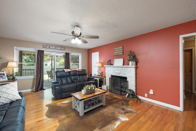 1704 E Latoka St, Springfield, MO 65804 - living area with ceiling fan, a stone fireplace, a textured ceiling, and wood finished floors