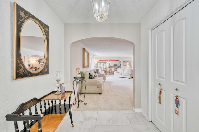 29 Trail Ridge Dr, Kimberling City, MO 65686 - hallway featuring arched walkways, light marble finish floors, a chandelier, a textured ceiling, and light colored carpet
