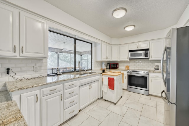 29 Trail Ridge Dr, Kimberling City, MO 65686 - kitchen with appliances with stainless steel finishes, white cabinetry, backsplash, a textured ceiling, and light stone counters