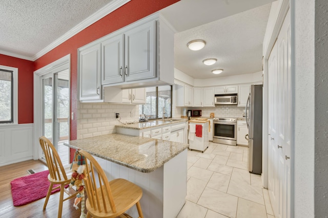 29 Trail Ridge Dr, Kimberling City, MO 65686 - kitchen with stainless steel appliances, a textured ceiling, a peninsula, tasteful backsplash, and a kitchen bar