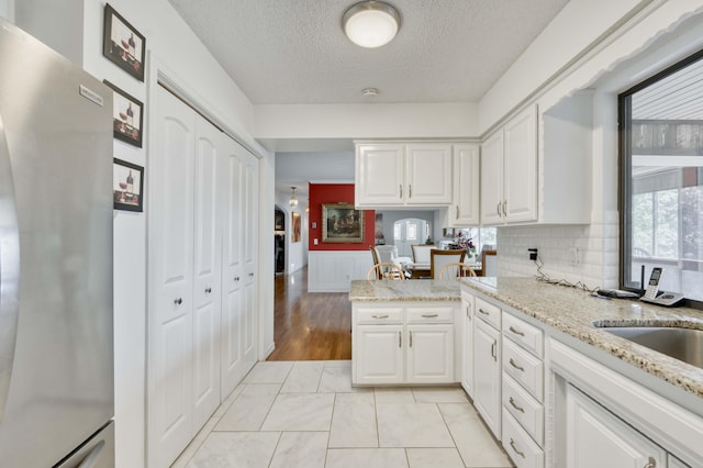 29 Trail Ridge Dr, Kimberling City, MO 65686 - kitchen featuring freestanding refrigerator, white cabinets, a textured ceiling, light stone counters, and tasteful backsplash