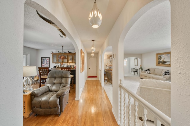 29 Trail Ridge Dr, Kimberling City, MO 65686 - hall featuring arched walkways, light wood-style floors, a textured ceiling, a chandelier, and a textured wall