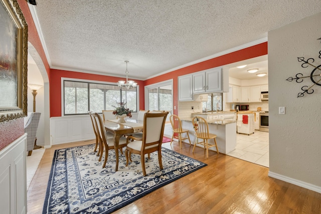 29 Trail Ridge Dr, Kimberling City, MO 65686 - dining area with a textured ceiling, a chandelier, crown molding, light wood finished floors, and arched walkways