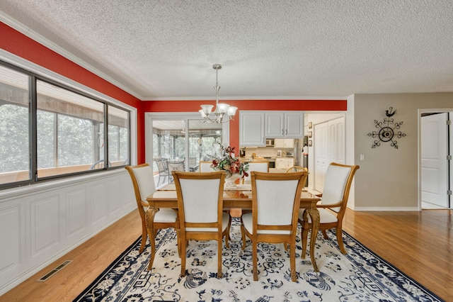 29 Trail Ridge Dr, Kimberling City, MO 65686 - dining space featuring a textured ceiling, a chandelier, light wood-type flooring, and crown molding
