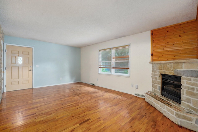 1111 S Lone Pine Ave, Springfield, MO 65804 - unfurnished living room featuring wood finished floors, a fireplace, and a textured ceiling