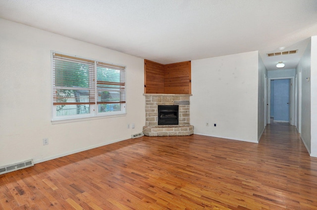 1111 S Lone Pine Ave, Springfield, MO 65804 - unfurnished living room featuring light wood-style flooring and a stone fireplace