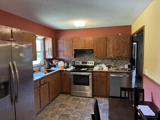 806 Lathrop Ave, Ava, MO 65608 - kitchen with appliances with stainless steel finishes, ventilation hood, decorative backsplash, brown cabinetry, and a textured ceiling