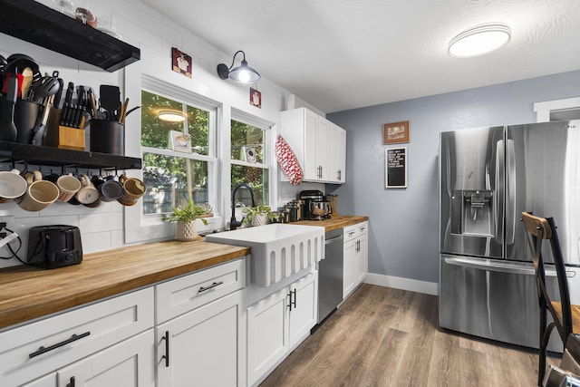 2019 N Rogers Ave, Springfield, MO 65803 - kitchen featuring stainless steel appliances, butcher block countertops, wood finished floors, white cabinets, and tasteful backsplash