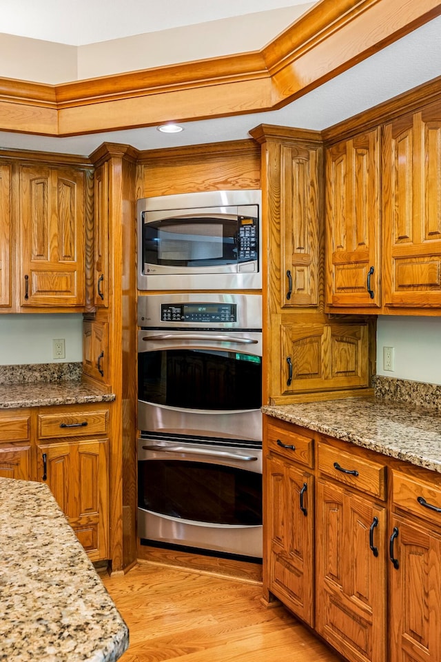 2347 E Nottingham St, Springfield, MO 65804 - kitchen featuring stainless steel appliances, brown cabinets, light wood-style flooring, and light stone countertops