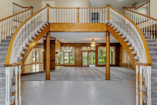 2347 E Nottingham St, Springfield, MO 65804 - carpeted entryway with a high ceiling, ceiling fan, stairs, tile patterned flooring, and wood walls