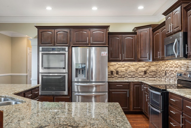 358 Spring View Pl, Reeds Spring, MO 65737 - kitchen with stainless steel appliances, arched walkways, light stone counters, dark brown cabinetry, and crown molding