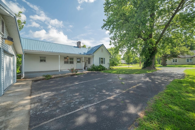 407 N Pine St, Pierce City, MO 65723 - view of front of house featuring a metal roof, covered porch, a chimney, and a front lawn