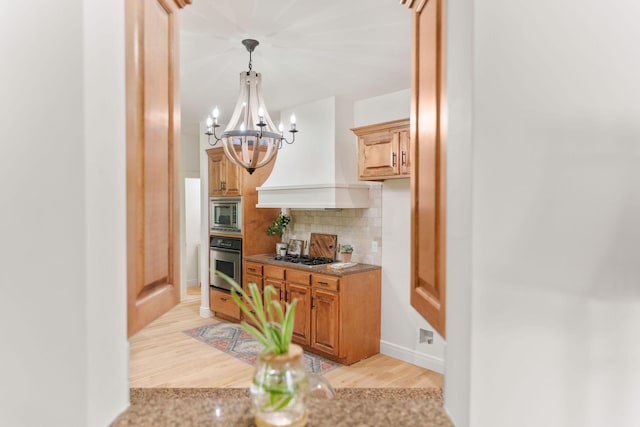 1303 E Eaglegate Pkwy, Springfield, MO 65804 - kitchen featuring stainless steel appliances, a chandelier, decorative backsplash, custom exhaust hood, and light wood finished floors