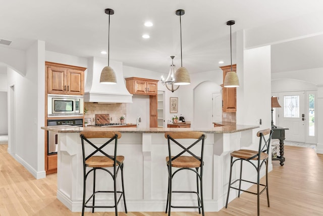 1303 E Eaglegate Pkwy, Springfield, MO 65804 - kitchen with stainless steel appliances, arched walkways, premium range hood, recessed lighting, and backsplash