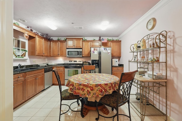 180 Grace Chapel Rd Unit 325, Blue Eye, MO 65611 - kitchen featuring stainless steel appliances, dark countertops, brown cabinets, crown molding, and light tile patterned floors