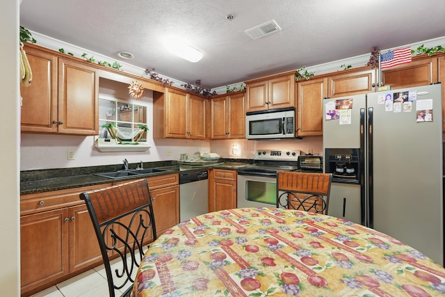 180 Grace Chapel Rd Unit 325, Blue Eye, MO 65611 - kitchen with appliances with stainless steel finishes, brown cabinetry, a textured ceiling, dark countertops, and light tile patterned floors