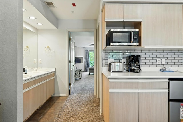 530 Spring Creek Ct Unit 5-10, Branson, MO 65616 - kitchen with stainless steel microwave, light brown cabinetry, light countertops, refrigerator, and backsplash