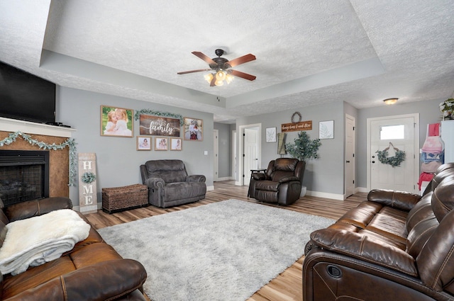 4531 W Somerset Dr, Battlefield, MO 65619 - living area featuring a textured ceiling, a tray ceiling, ceiling fan, wood finished floors, and a fireplace