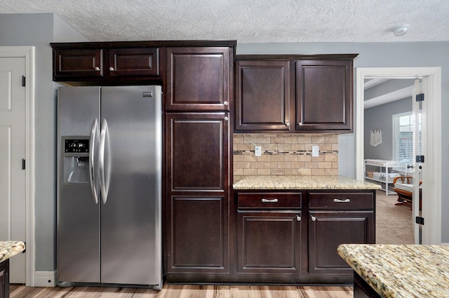4531 W Somerset Dr, Battlefield, MO 65619 - kitchen with stainless steel refrigerator with ice dispenser, dark brown cabinets, a textured ceiling, decorative backsplash, and light stone countertops