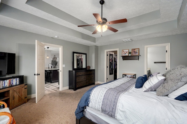 4531 W Somerset Dr, Battlefield, MO 65619 - bedroom featuring a tray ceiling, a walk in closet, light colored carpet, a closet, and a textured ceiling