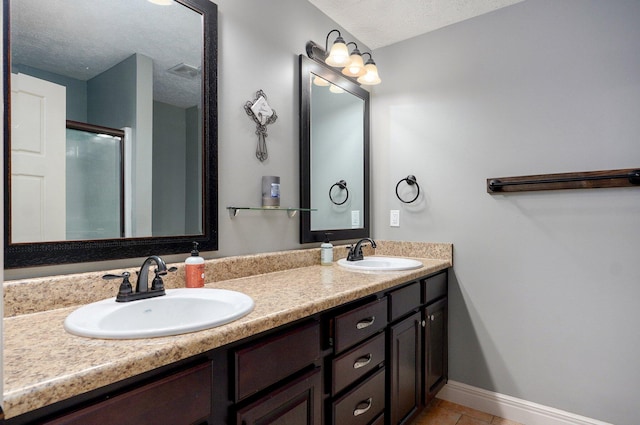 4531 W Somerset Dr, Battlefield, MO 65619 - bathroom with a textured ceiling, double vanity, tile patterned floors, and a shower with shower door