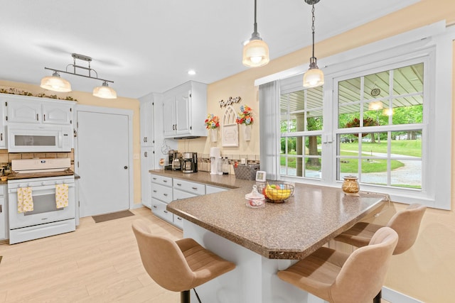 1850 E Farm Road 88, Springfield, MO 65803 - kitchen with white appliances, a peninsula, white cabinetry, a breakfast bar area, and recessed lighting