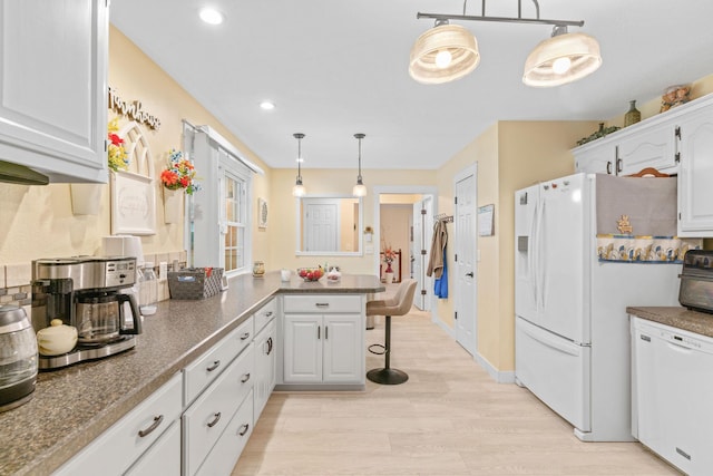 1850 E Farm Road 88, Springfield, MO 65803 - kitchen with white appliances, a peninsula, dark countertops, a breakfast bar area, and light wood-style floors