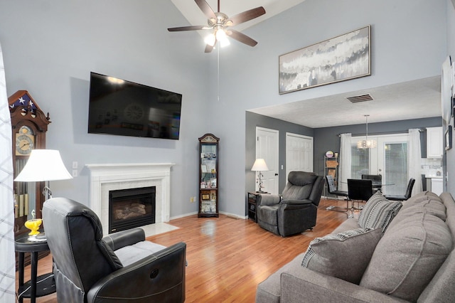 801 S Creekwood Ct, Nixa, MO 65714 - living area featuring a high ceiling, ceiling fan, light wood finished floors, a chandelier, and a premium fireplace