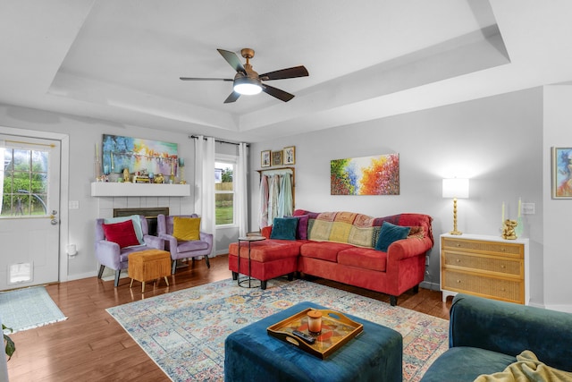 676 E Gallup Hill Rd, Nixa, MO 65714 - living room featuring a tray ceiling, ceiling fan, wood finished floors, and a tiled fireplace
