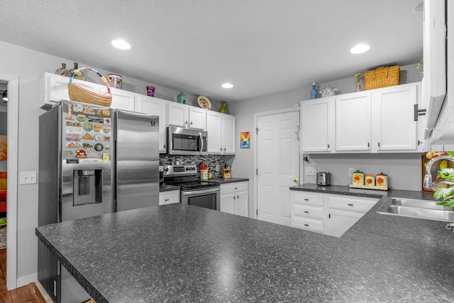 676 E Gallup Hill Rd, Nixa, MO 65714 - kitchen featuring appliances with stainless steel finishes, white cabinetry, dark countertops, recessed lighting, and a peninsula